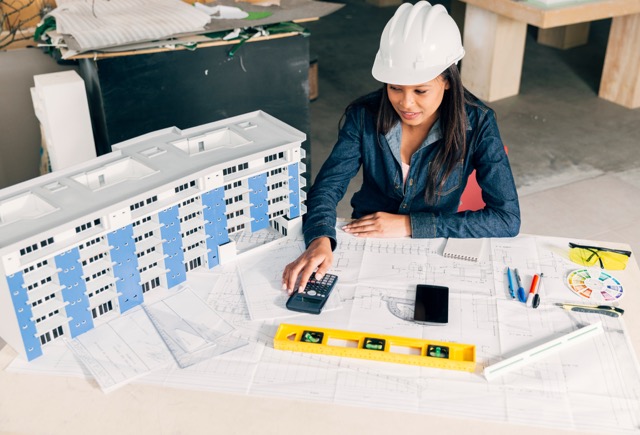 MEP engineer reviewing drawings and a physical building model for a construction project