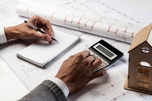 Engineer performing value engineering and bid planning with blueprints, a calculator, and a notepad