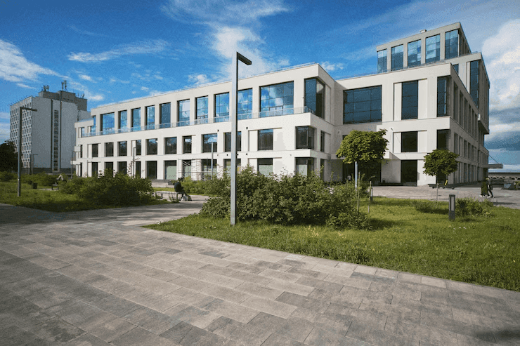 Modern multi-story office building with large windows and a paved walkway in front