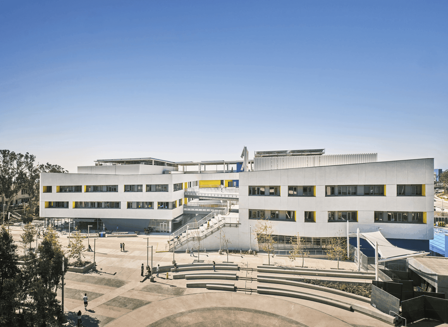 Exterior of a modern university or school campus with a large plaza and tiered seating