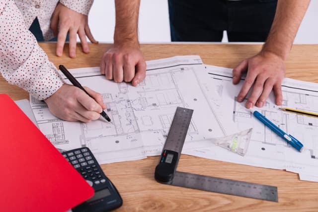 Engineering team reviewing construction documents and plans to meet permit requirements