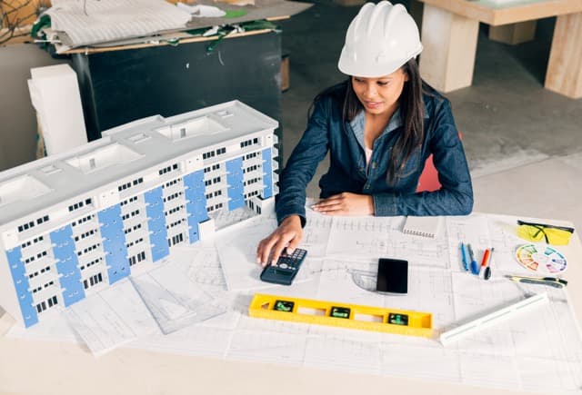 MEP engineer reviewing drawings and a physical building model for a construction project