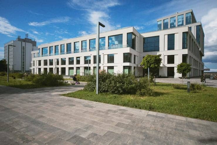 Modern multi-story office building with large windows and a paved walkway in front