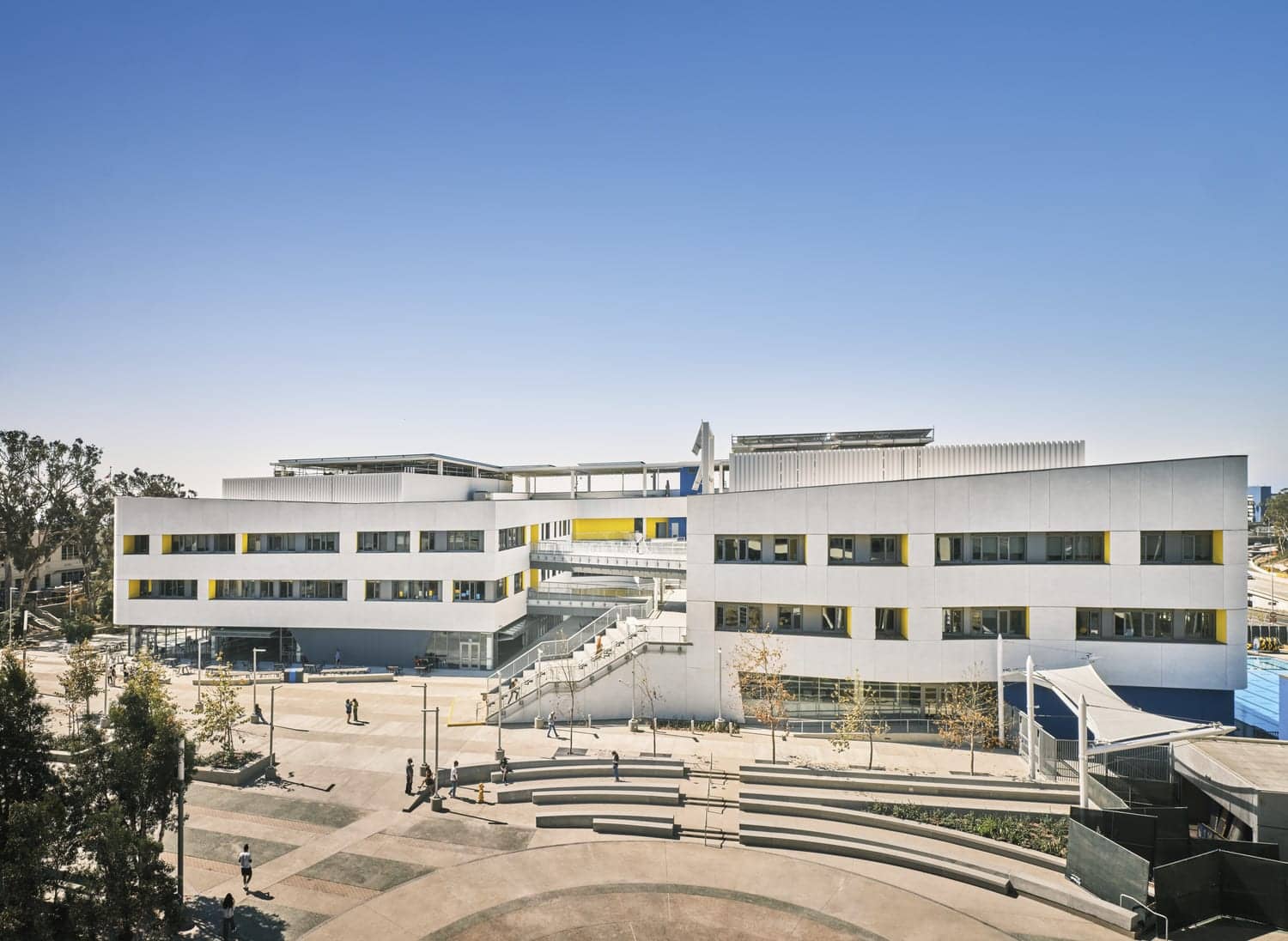 Exterior of a modern university or school campus with a large plaza and tiered seating